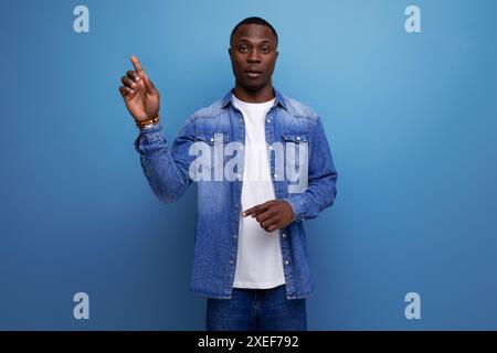 Porträt eines jungen gutaussehenden, klugen afrikaners in einer Jeansjacke, die von einer Idee auf Studiohintergrund inspiriert wurde Stockfoto