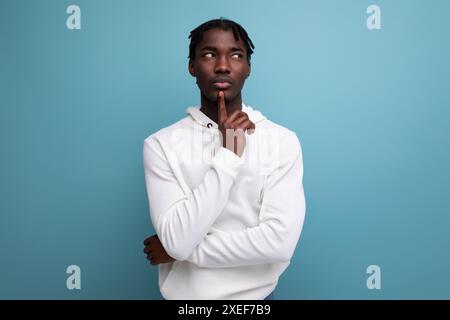 Das nachdenkliche Model dunkelhäutiger junger brünette Mann schaut in einem weißen Pullover weg Stockfoto