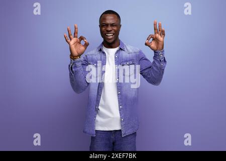 Porträt eines jungen gutaussehenden, klugen afrikaners in einer Jeansjacke, die von einer Idee auf Studiohintergrund inspiriert wurde Stockfoto