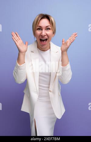 Junge fröhliche positive Blondie elegante weibliche Erwachsene mit Jacke und Kleid Stockfoto