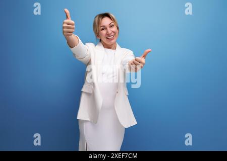 Elegante blonde junge europäische Frau in einer weißen Jacke und Kleid auf einem isolierten Hintergrund Stockfoto
