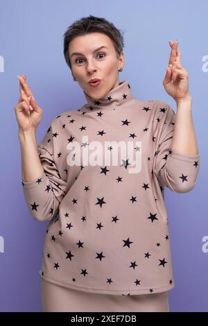 Gut gepflegte junge Karrierefrau mit grauem, gestreiftem Haar in Rock und Bluse, in der Hoffnung auf Glück Stockfoto