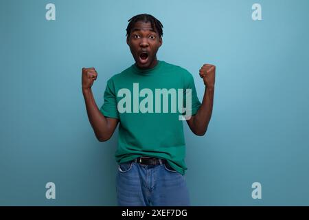 Selbstbewusstes Brünette-Modell stilvoller dunkelhäutiger Mann in Dreadlocks in einem coolen T-Shirt auf blauem Hintergrund Stockfoto