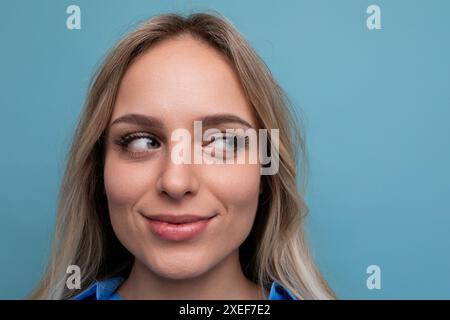 Foto einer entzückenden, lässigen jungen Frau mit lächelnden Augen auf blauem Hintergrund Stockfoto