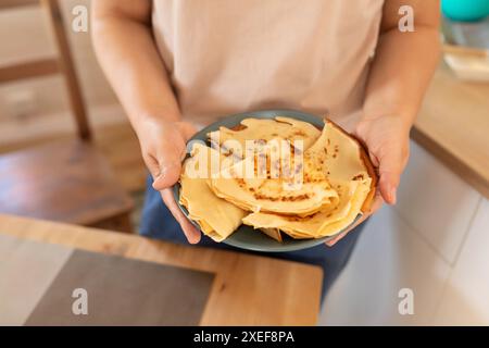 Eine Frau legt Pfannkuchen auf den Teller Stockfoto