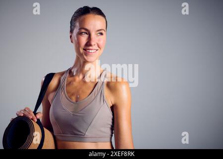 Studio-Porträt Der Lächelnden Frau Im Fitnessstudio Fitness-Kleidung, Die Eine Trainingsmatte Trägt Stockfoto