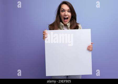 Glückliche junge brünette Frau, die Pappkarton mit Mockup hält Stockfoto