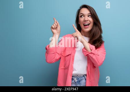 Stilvolle Brünette Frau im trendigen Hemd freut sich auf Studiohintergrund Stockfoto