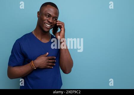 Junger amerikanischer Mann in blauem T-Shirt, der am Telefon spricht Stockfoto
