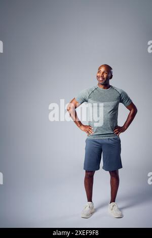 Studio-Porträt Des Lächelnden Reifen Mannes In Gym Fitness Kleidung Falten Arme Vor Grauem Hintergrund Stockfoto