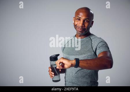 Studio-Porträt Des Reifen Mannes Im Fitnessstudio Fitness-Bekleidung Streaming Zu Kabellosen Ohrhörern Von Smart Watch Stockfoto