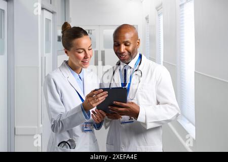 Männliche Und Weibliche Ärzte, Die Weiße Mäntel Im Krankenhaus Tragen Und Auf Das Digitale Tablet Schauen Stockfoto