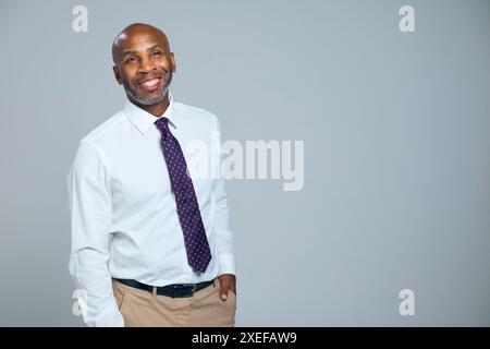 Studio-Porträt Des Lächelnden Reifen Geschäftsmannes, Der Krawatte Vor Grauem Hintergrund Trägt Stockfoto