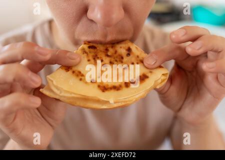 Frau beißt Mehlpfannkuchen beim Frühstück ab Stockfoto