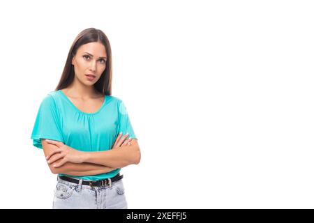 Junge gut gepflegte kaukasische Brünette Frau mit langen Haaren in einem blauen T-Shirt isoliert auf weißem Hintergrund mit Kopierraum Stockfoto
