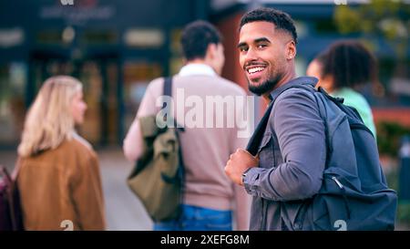 Porträt Eines Männlichen Universitätsstudenten, Der Mit Freunden Vor Dem College Über Die Schulter Schaut Stockfoto