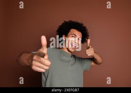 Foto-Porträt des netten jungen Mannes tanzend Punkt Sie tragen trendiges Khaki-Outfit isoliert auf braunem Hintergrund Stockfoto