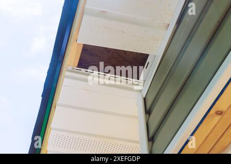 Installation von Kunststoffpaneelen aus Vinyl-Soffit an der Fassadendecke des neuen Hauses durch einen Mitarbeiter Stockfoto