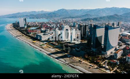 Küstenstadt mit modernen Hochhäusern, malerischem Strand und Bergen im Hintergrund. Blick aus der Vogelperspektive auf das moderne Zentrum von Batumi, riesiger Hotelkomplex in Orbi City an der Schwarzmeerküste. Georgia, Batumi, Februar 2023. Stockfoto