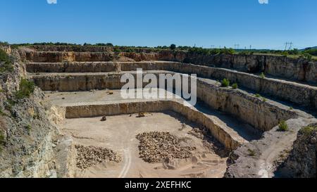Bagger zur Förderung von Kalkstein in einem Tagebau, umgeben von Wald an einem sonnigen Tag Stockfoto