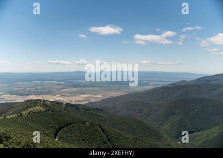 panoramablick auf ein ausgedehntes Tal, umgeben von sanften Hügeln, die in warmes Sonnenlicht getaucht sind und die Schönheit der Natur zum Ausdruck bringen Stockfoto