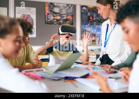Staunender männlicher Sekundar- oder High School-Schüler, der VR-Headset in der Wissenschaftsklasse mit weiblicher Lehrerin trägt Stockfoto