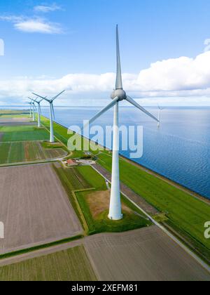 Ein Windpark aus hoch aufragenden Turbinen steht anmutig inmitten eines riesigen Wassers, ein ruhiges und nachhaltiges sig Stockfoto