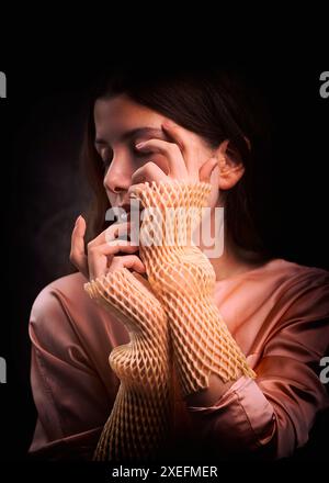 Junge Frau in rosa Bluse und rosafarbenen Muffen, die die Hände bedecken, spanien Stockfoto