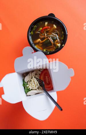 Nudeln mit Schweinefleisch und Gemüse in Take-out Box auf Holztisch Stockfoto