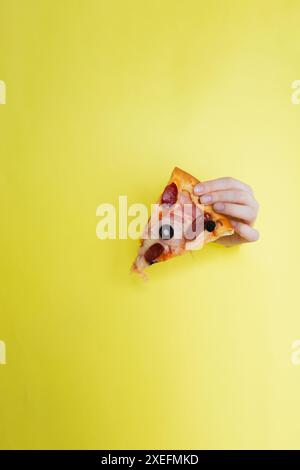 Petite Pizza auf gelbem Hintergrund mit Hand Stockfoto