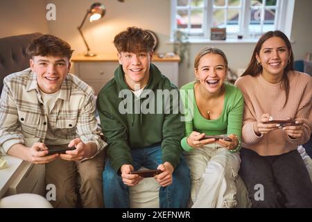 Porträt Einer Gruppe Von Jugendlichen Mädchen Und Jungen Zu Hause Im Schlafzimmer Gemeinsam Gaming Auf Mobiltelefonen Stockfoto