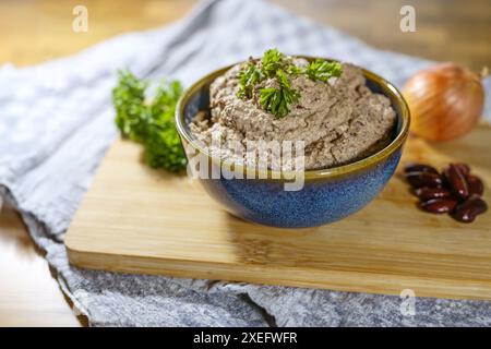 Veganer Dip auf Pflanzenbasis, der an Leberwurst erinnert, hausgemacht aus Kidneybohnen, Tofu, Zwiebeln und Kräutern, serviert in einer Schüssel mit Petersilie-Beilage o Stockfoto