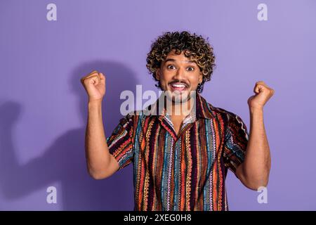 Porträt des netten jungen Mannes, die Fäuste tragen Hemd isoliert auf lila Hintergrund Stockfoto