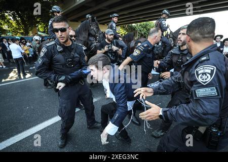 Orthodoxe Juden blockieren Highway gegen Wehrpflicht in Isra BNEI BRAK, ISRAEL - 27. JUNI: Dutzende ultraorthodoxe Juden, auch bekannt als Haredim, stoßen am 27. Juni 2024 mit der israelischen Polizei zusammen, während sie einen Sit-in-Protest gegen den Militärdienst auf der Autobahn in Bnei Brak, Israel, veranstalten. Foto: saeed qaq Copyright: XSAEEDQAQx image00008.jpeg Stockfoto