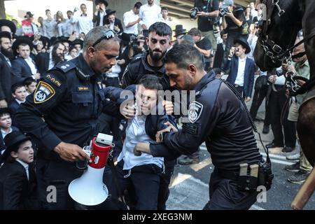 Orthodoxe Juden blockieren Highway gegen Wehrpflicht in Isra BNEI BRAK, ISRAEL - 27. JUNI: Dutzende ultraorthodoxe Juden, auch bekannt als Haredim, stoßen am 27. Juni 2024 mit der israelischen Polizei zusammen, während sie einen Sit-in-Protest gegen den Militärdienst auf der Autobahn in Bnei Brak, Israel, veranstalten. Foto: saeed qaq Copyright: XSAEEDQAQx image00005.jpeg Stockfoto