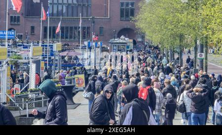 Eine lebhafte Szene entfaltet sich, während eine große Gruppe von verschiedenen Personen gemütlich durch eine geschäftige Stadtstraße schlendert und eine dynamische Atmosphäre schafft Stockfoto