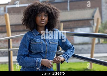 Selbstbewusste junge Frau im lässigen Denim-Outfit, angelehnt an Geländer Stockfoto