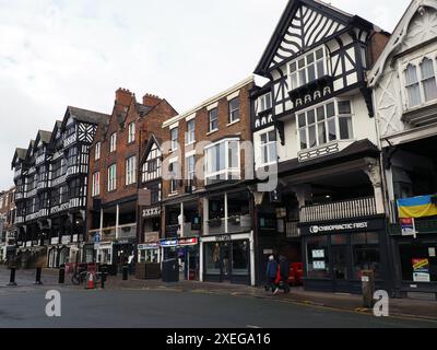 Leute, die an Geschäften und Bars in der Bridge Street Chester vorbeilaufen Stockfoto