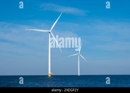 Drei kolossale Windturbinen stehen hoch und majestätisch in der Weite des Ozeans und nutzen die kraftvolle Energie des Sieges Stockfoto