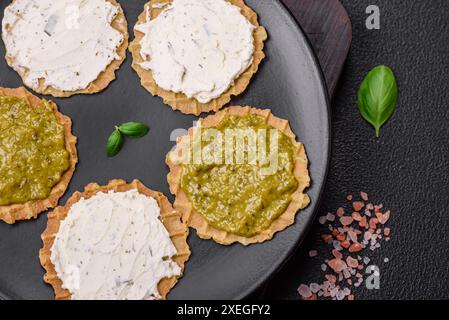 Runde Snacks mit knusprigen Chips oder Cracker mit Frischkäse und Pesto Stockfoto