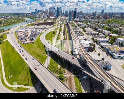 Calgary Skyline aus der Luft mit Blick auf den Pendlerverkehr und erhöhte Linien des öffentlichen Nahverkehrs mit kanadischen Wahrzeichen im Hintergrund in Alberta Kanada. Stockfoto