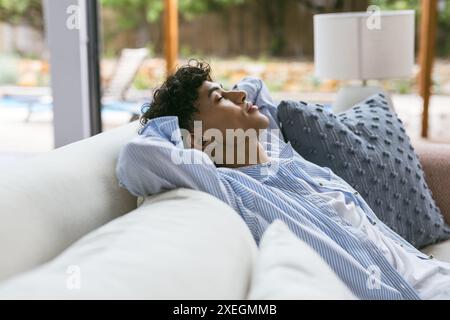 Entspannend auf der Couch, Teenager in gestreiftem Hemd mit geschlossenen Augen Stockfoto