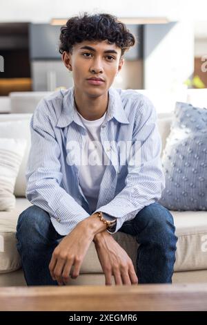 Auf der Couch sitzend, Teenager in lässiger Kleidung und in die Kamera schauend Stockfoto