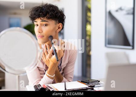 Make-up mit Pinsel auftragen, Transgender-Transgender-Frau, die zu Hause im Spiegel schaut Stockfoto