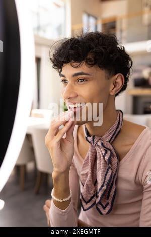 Lippenstift auftragen, Transgender-Transgender-Frau lächelt und zuhause in den Spiegel blickt Stockfoto