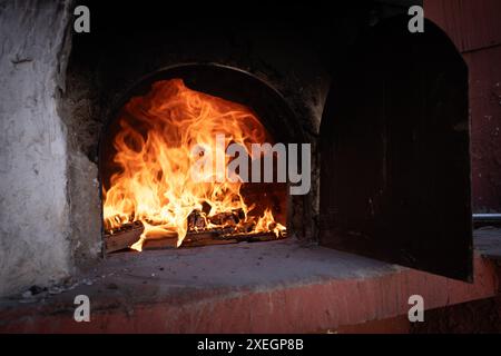 Feuer und verbrenne Kohle im Steinofen. Ofen aus Ziegeln und Ton. Stockfoto