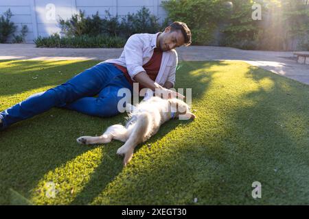 Entspannen auf Gras, Mann streichelt Hund im Garten, genießt sonnigen Tag Stockfoto