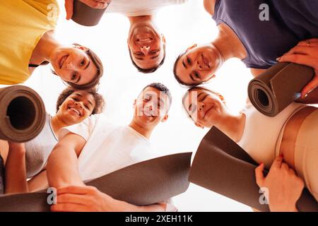Multirassisch lächelnde Menschen mit Matten nach Yoga in einem Fitnessclub. Eine Gruppe junger sportlicher Frauen und Männer nach körperlicher Ex Stockfoto