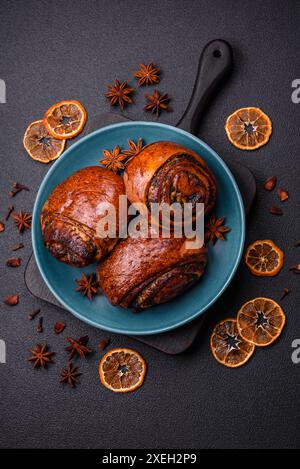 Köstliche frisch gebackene Brötchen mit Mohn und Zimt auf einer Keramikplatte Stockfoto