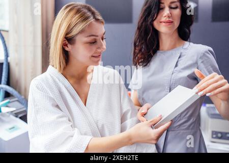 Die hübsche weiße Kosmetikerin kommuniziert mit ihrer Klientin. Stockfoto
